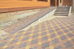 Building ramp for wheelchair entry and stairs with colorful pavers. Pavement.