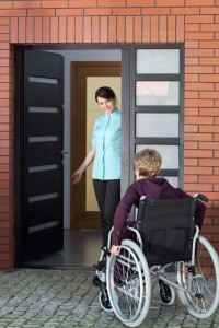 Female caregiver inviting elderly woman on wheelchair to nursing home