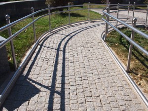 Ramp for physically challenged from the granite pavement on a sunny summer day with midday shadows